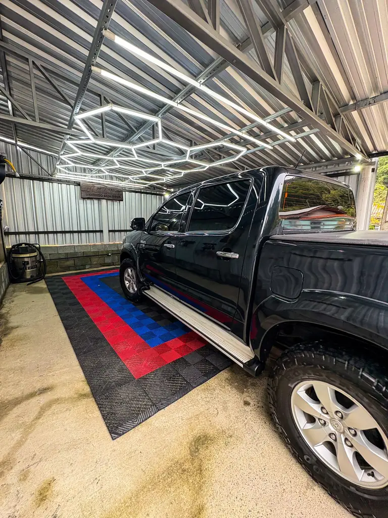 Picape preta com vidros escuros estacionada sob o teto de LED hexagonal da GL.